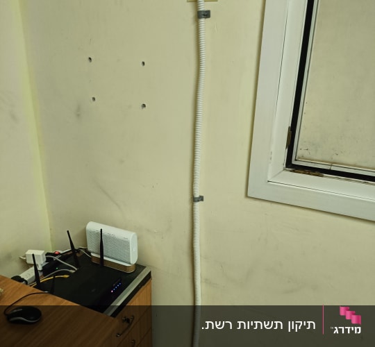 נתב עם אנטנות על שולחן ליד כבל חשמל